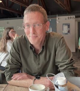 Man smiling at café table.